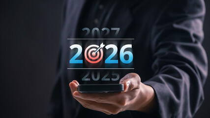 Businessman holding mobile device showing 2026 target goal, symbolizing future planning, vision,...