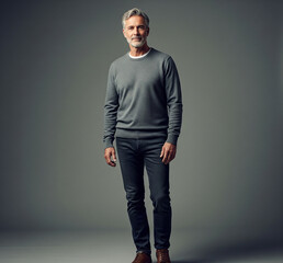 Obraz premium Confident mature man in casual attire stands against a neutral background.