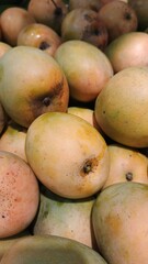 Close up pile of tasty fresh mangoes sold at the market as a background.