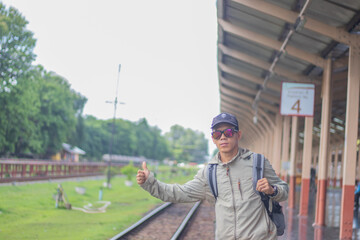 Confident young latin man standing alone at sunrise. Standing on train station platform, holding...