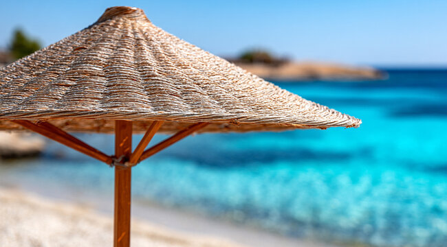 A straw umbrella from the sun on a turquoise beach. - Powered by Adobe