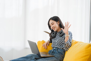 Online Connect: A youthful woman, immersed in a virtual meeting, offers a friendly wave, seated on...