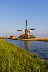 Naklejka premium Traditional Dutch windmill standing on the bank of a canal in North Holland, Netherlands