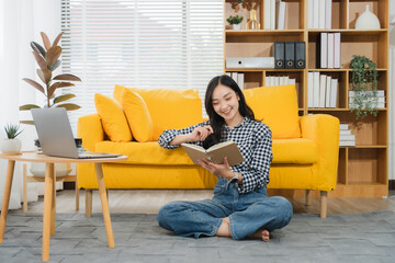 Cozy Corner: A woman enjoys her leisure time at home, immersed in a book on the floor, surrounded...