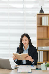 Focused in the workplace: A focused young professional woman engrossed in reading a book with...