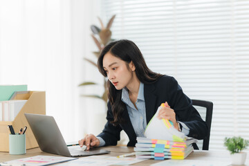 Focused at Work: A determined woman diligently works at a laptop in a well-lit office environment,...