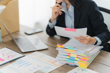 Focused Professional: A focused professional meticulously reviews documents at their desk,...