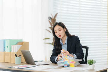 Focused Professional: A sharp, young woman in business attire is seen engrossed in reviewing...