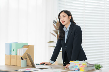 Woman at Office: A young professional woman in a tailored suit stands confidently at her desk, her...