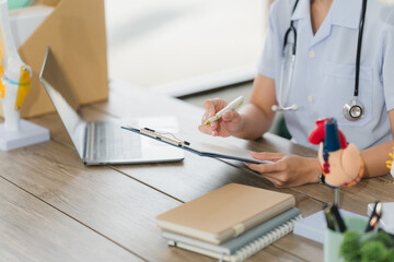 Healthcare Professional at Work: A dedicated healthcare professional, immersed in their work, is focused on documenting important health records in their clinic.