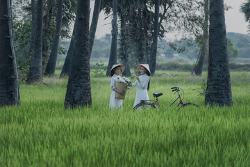 Beautiful Vietnamese Asian woman wearing White color Ao Dai National Costume Dress with red bicycle in rice fields. Portrait fashion show in nature.