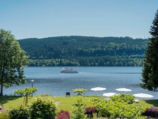 Titisee-Neustadt im Südschwarzwald. Grünflächen und Blumengärten des Thermalparks mit außergewöhnlichem Blick auf den See mit seinen Ausflugsbooten von Norden nach Süden
