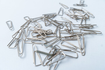 Close-up of scattered silver paper clips on a clean white surface. Captures the simplicity and...