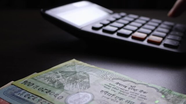 Macro shot of calculator and nepalese rupee (NPR) banknotes. Concept of bank office work, saving money for retirement, cash settlement, financial success, literacy and income planning in Nepal.