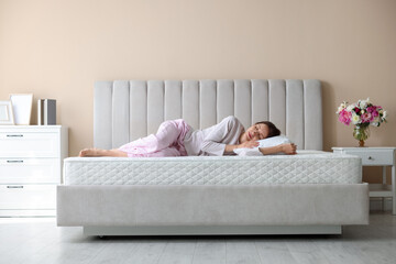 Woman sleeping on bed with orthopedic mattress at home