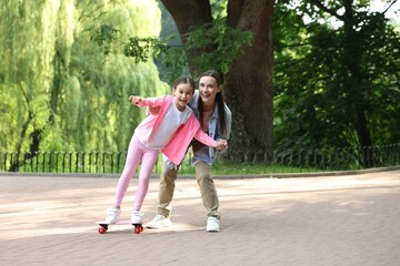 Obraz premium Family getaway. Happy mother and daughter having fun with penny board in park