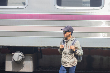 Confident young latin man standing alone at sunrise. Standing on train station platform, holding...