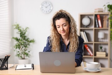 Woman working with laptop at desk in home office