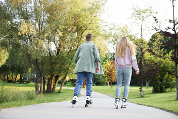 Couple roller skating together in park on summer day