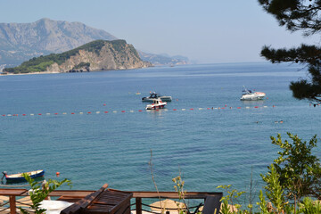 Picturesque Mogren Beach in Budva, Montenegro, with Sunbeds, Umbrellas, and Sveti Nikola Island View