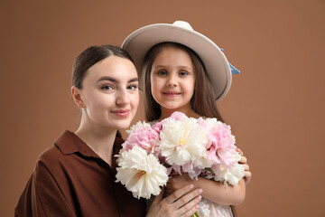 Mother and her daughter with bouquet of beautiful peonies on brown background