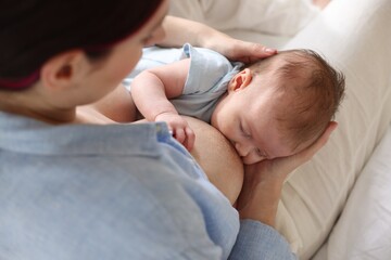 Mother breastfeeding her newborn baby indoors, above view