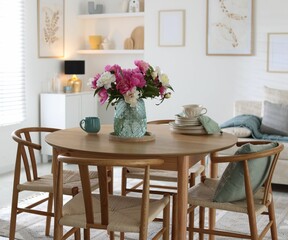 Dining table with beautiful flowers and dishware in room. Interior design
