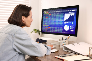 Stock exchange. Woman analysing financial market on computer at wooden table indoors