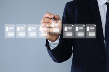 Human resources manager checking candidate's resume on virtual screen against grey background,...