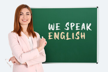 Teacher near green chalkboard with text We Speak English. Language course