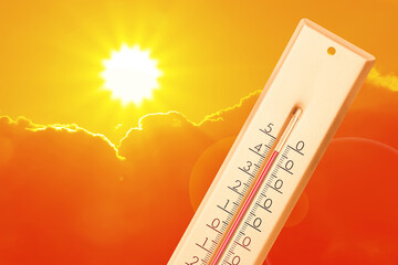 Extremely high temperature on thermometer against orange sky on sunny day. Severely hot summer...