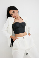 young woman posing in stylish black corset and white suit, modern fashion, confident posture,...