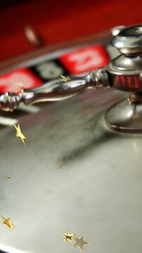 Composite video of multiple golden star icons falling against close up of russian roulette spinning