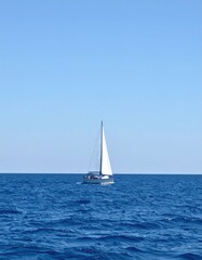 Fototapeta premium Sailboat on ocean, bright blue sky, sunny day