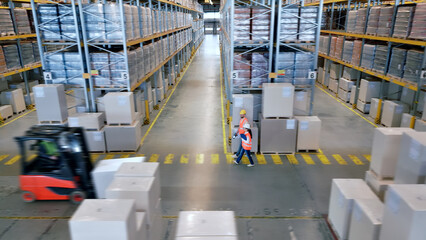 Aerial view of a busy cargo warehouse where workers navigate aisles, symbolizing global supply chain efficiency and teamwork amidst towering shelves and forklifts. © stockcopter