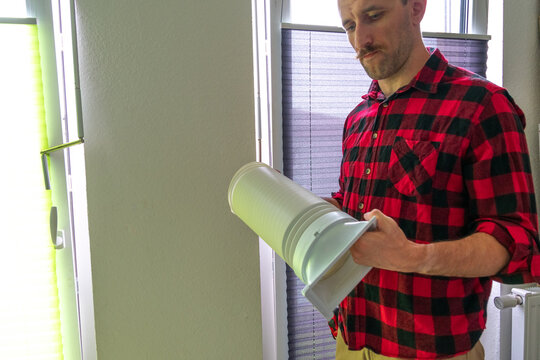 A white man installing the hose of a portable air conditioner at home, close-up