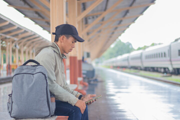 Confident young latin man standing alone at sunrise. Standing on train station platform, holding...