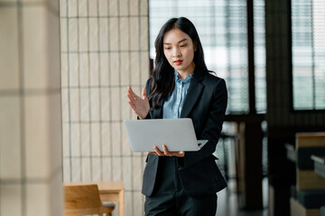 Asian businesswoman having video call using laptop in modern office