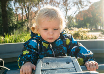A baby is sitting on a bench in a park