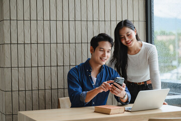 Asian entrepreneurs working together on a project using smartphone and laptop