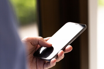 Close-up of human hand holding modern smartphone with blank screen, suitable for technology, communication, and mobile lifestyle concepts.