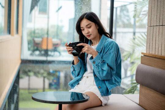 Young photographer reviewing photos on camera in modern cafe