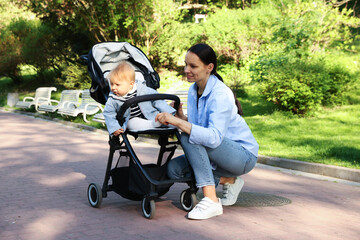 Mother with her cute baby in stroller at park