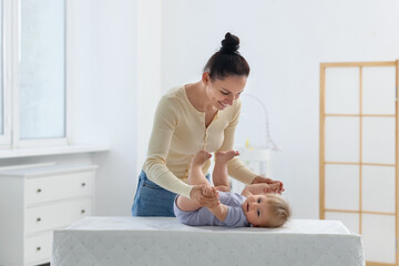 Mother playing with her cute baby on changing table at home