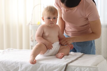 Mother changing her baby's diaper on table at home