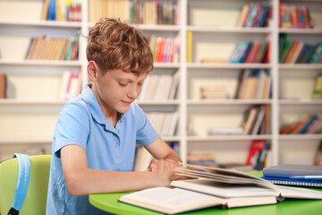 Student with books studying at table in library. Space for text