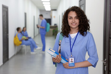 Medical student in uniform with books indoors, selective focus