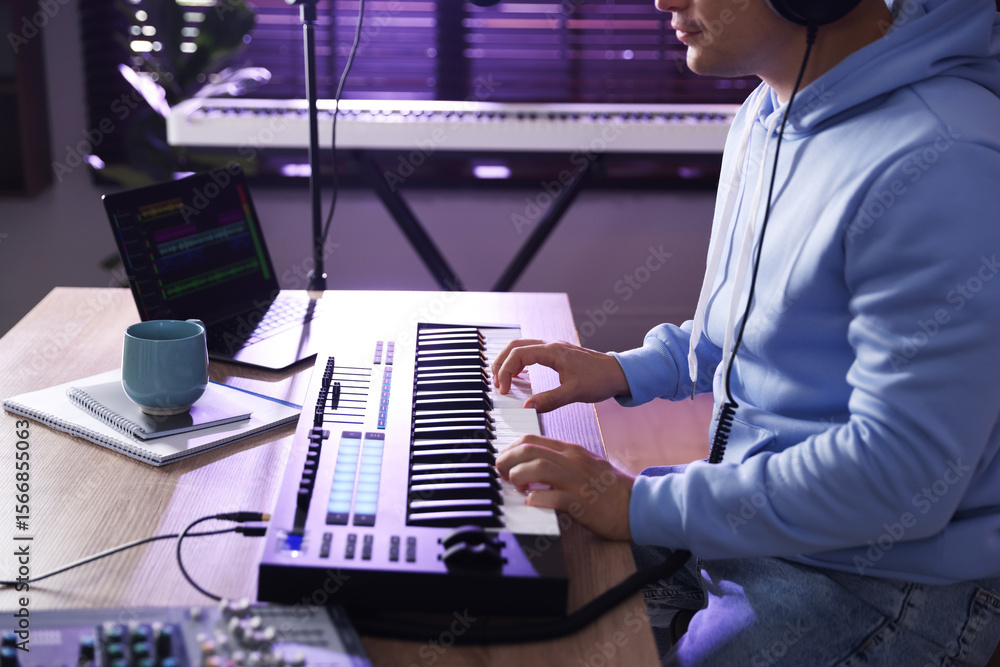 Aufkleber man working with midi keyboard at table in home studio, closeup