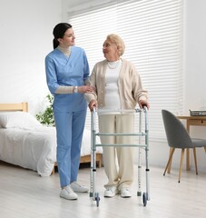 Fototapeta premium Nurse assisting senior woman with walking frame indoors. Home health care service