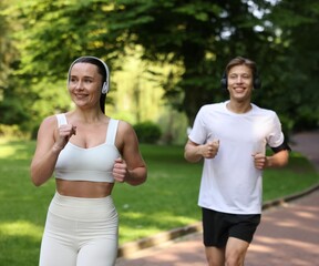 Sporty couple with headphones running in park